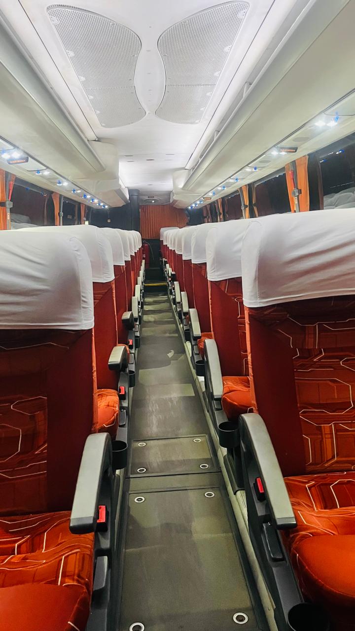 Pasillo interior de un bus con asientos rojos